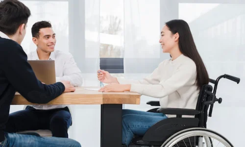 smiling-young-woman-sitting-wheelchair-having-corporate-business-meeting-with-his-two-colleague_23-2148127349