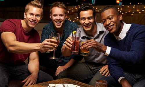 Portrait Of Male Friends Enjoying Night Out At Rooftop Bar